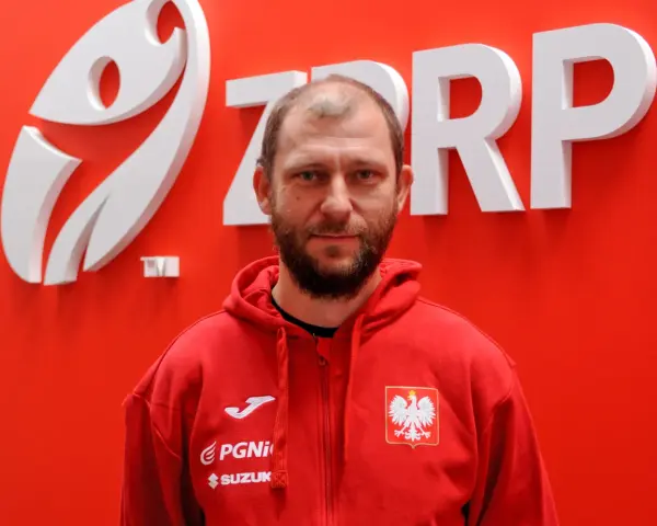 Marcin Wichary, w czerwonej bluzie z orłem, przed logo ZRP.