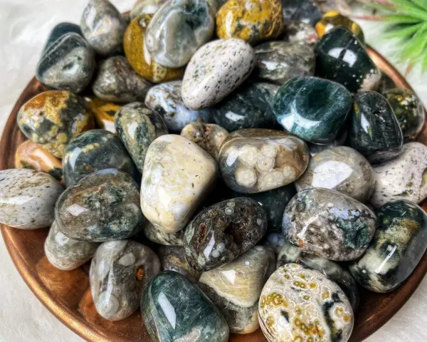 Montón de piedras jaspe blanco pulidas, con vetas verdes, marrones y amarillas. Sus propiedades son conocidas por su conexión con la naturaleza.