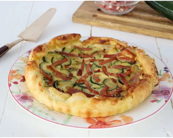 Torta salata con zucchine e speck, dorata e invitante, pronta per essere gustata.