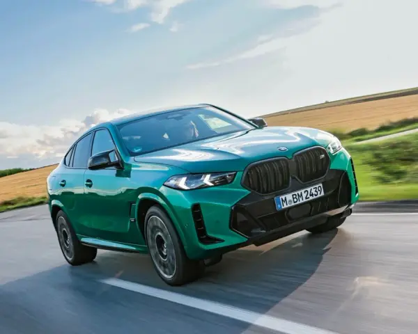 Zielony suv coupe pędzi po drodze, otoczony polami i błękitnym niebem.