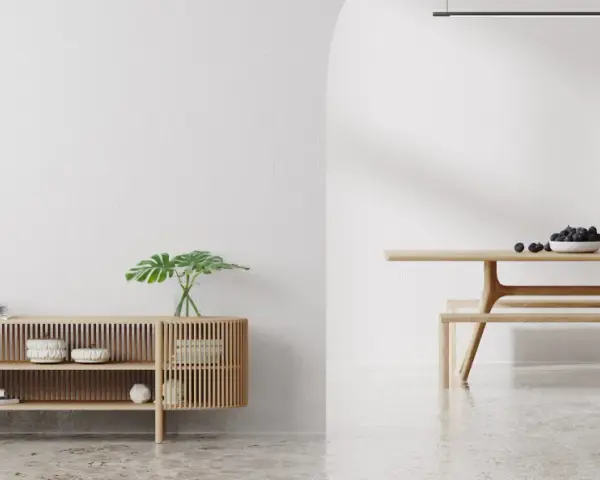 Un espacio minimalista con un aparador de madera y un comedor. Las paredes lisas y el suelo pulido crean un ambiente sereno.