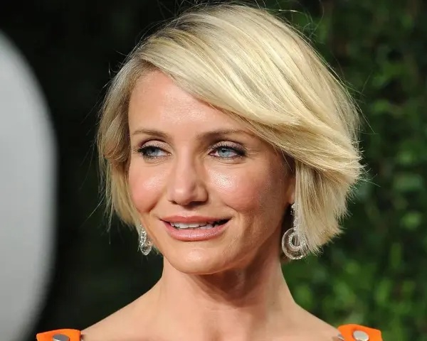 Cameron Diaz w stylowej fryzurze bob, idealnej dla okrągłej twarzy po 50. roku życia, z błyszczącymi kolczykami.