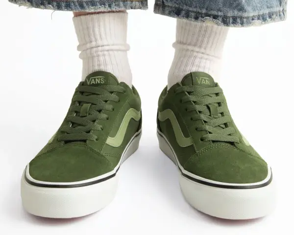 Zielone trampki Vans z jasną falą. Czy to rozmiar buta 11.5 cm? Białe skarpetki i podarte jeansy dopełniają stylizację.