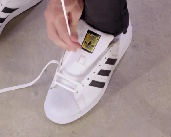 Pokazuję, jak wiązać sznurówki w adidasach Superstar. Białe sznurówki przeplatane przez czarne paski.
