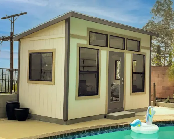 A modern shed, perfect to build a backyard oasis, sits by a pool with a unicorn float.