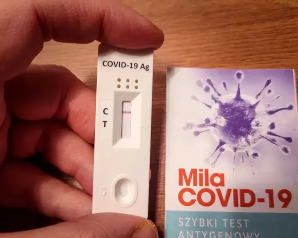 Szybki test antygenowy COVID-19 z jedną kreską kontrolną. Obok opakowanie z grafiką wirusa.