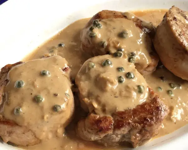 Cuatro medallones de solomillo a la pimienta en una cremosa salsa con granos de pimienta verde.