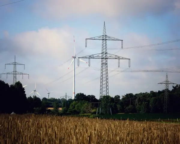 Wiatraki i linie energetyczne na tle nieba. OZE w Polsce to przyszłość, która już dziś zasila nasze domy.