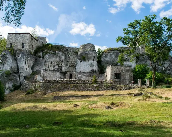 Kamienny zamek morsko wznosi się na skale, otoczony zielenią. Ruiny i mury tworzą malowniczy krajobraz.