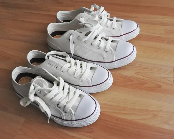 Cuatro zapatillas blancas de lona, listas para limpiar y lucir impecables.