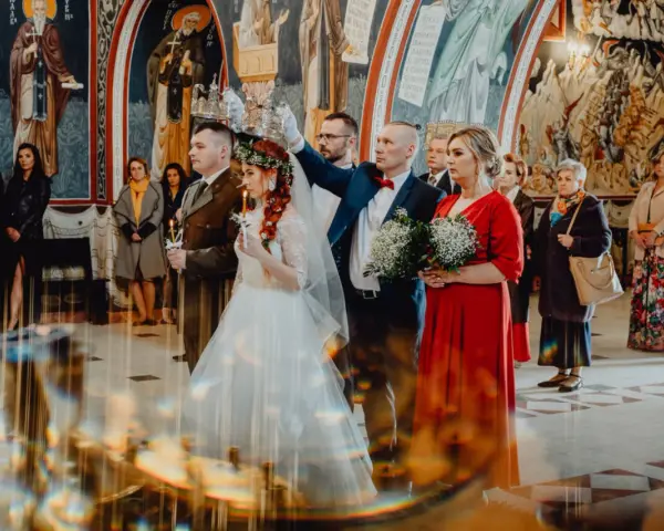 Para młoda podczas ceremonii ślubu prawosławnego. Pan młody w mundurze, panna młoda w bieli. Nad nimi trzymane są korony.