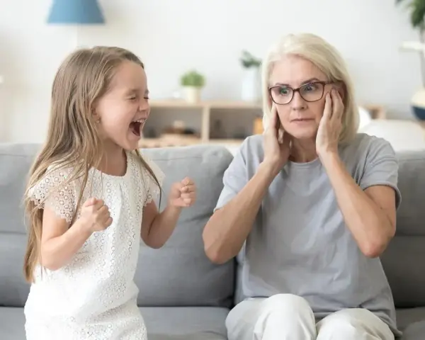 Mała dziewczynka krzyczy, gdy dziecko rządzi rodzicami. Babcia zatyka uszy, wyraźnie zirytowana.