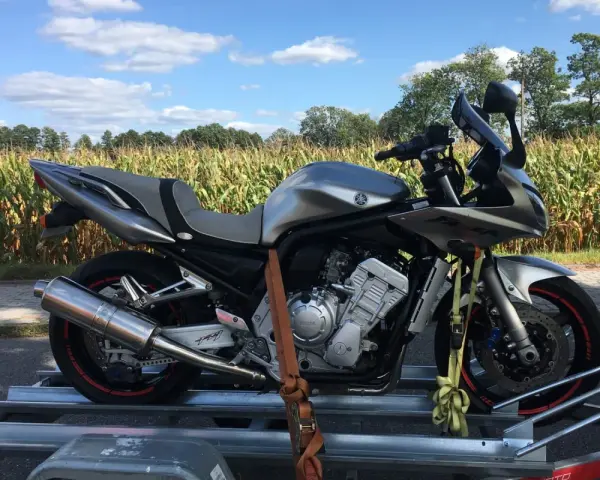 Srebrny motocykl na przyczepce, gotowy do transportu. Idealne tanie motocykle z Niemiec dla każdego fana dwóch kółek.