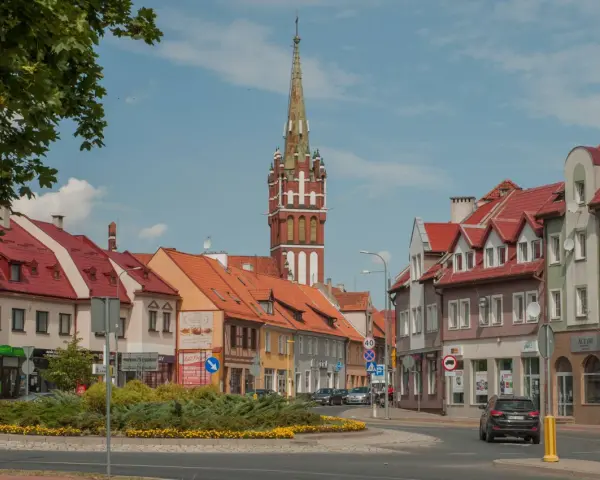 Kętrzyn atrakcje: malowniczy rynek z charakterystyczną wieżą kościelną, kolorowe kamienice i zielone skwery.