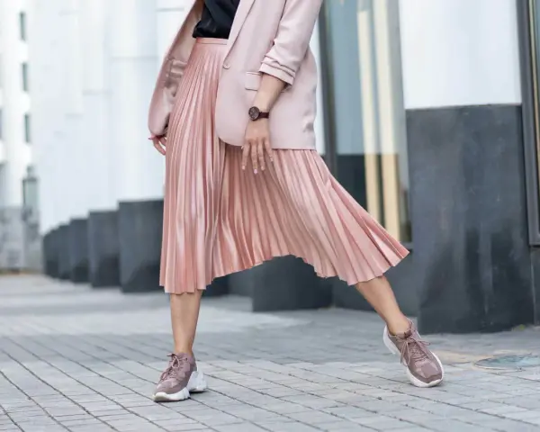Różowa spódnica plisowana w stylizacji z marynarką i sneakersami. Elegancko i na luzie.