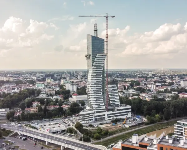 Wielka, kręcona wieża góruje nad miastem. To najwyższy budynek mieszkalny w Polsce, wciąż w budowie, z dźwigiem na szczycie.