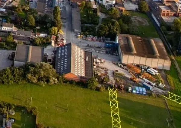Vue aérienne d'un lotissement et d'une zone industrielle. Un pylône jaune est visible, marquant un emplacement réservé pour le droit de délaissement.