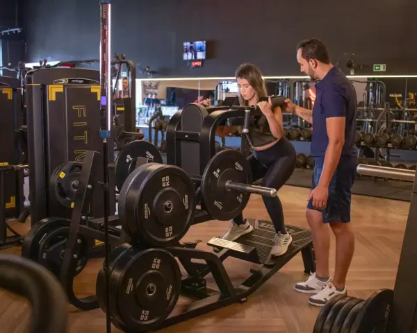 Kvinna utför benpress med instruktör som övervakar. En del av ett effektivt bro split-träningspass.