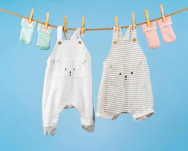 Ropa de bebé colgada para secar: dos peleles con caritas de oso y calcetines a juego. ¡El momento perfecto para saber cuando lavar la ropa del bebé!