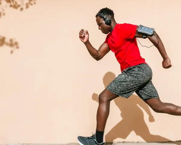 Hombre corre con audífonos y brazalete para celular. ¡Correr quema grasa y te da energía!