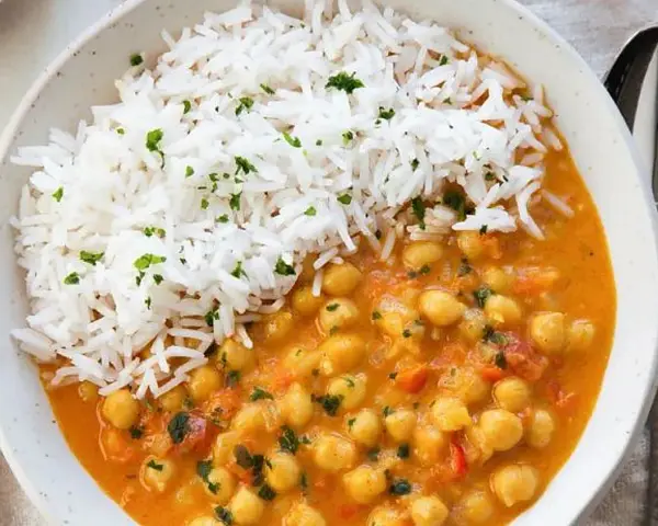 Un delicioso curry de garbanzos con arroz blanco esponjoso, espolvoreado con perejil fresco.