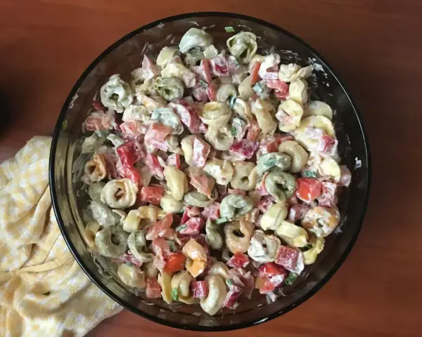 Kolorowa sałatka z tortellini, papryką i majonezem w szklanej misce.