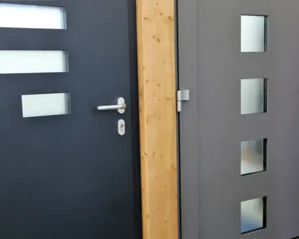 Dwie nowoczesne drzwi wejściowe, jedna ciemnoszara z prostokątnymi przeszkleniami, druga szara z kwadratowymi. Dowiedz się, jak uszczelnić drzwi wejściowe.