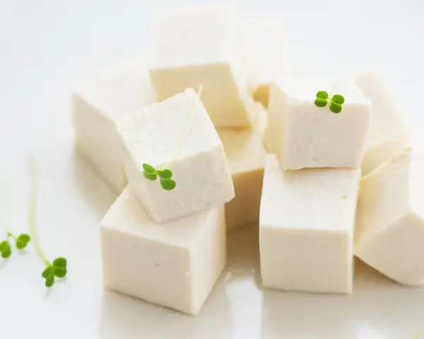 Kostki białego tofu, idealna podstawa do wielu dań, ozdobione świeżymi kiełkami.
