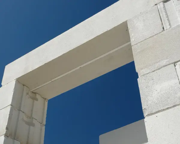 Białe nadproże nad drzwiami 90, wykonane z bloczków z betonu komórkowego, na tle błękitnego nieba.