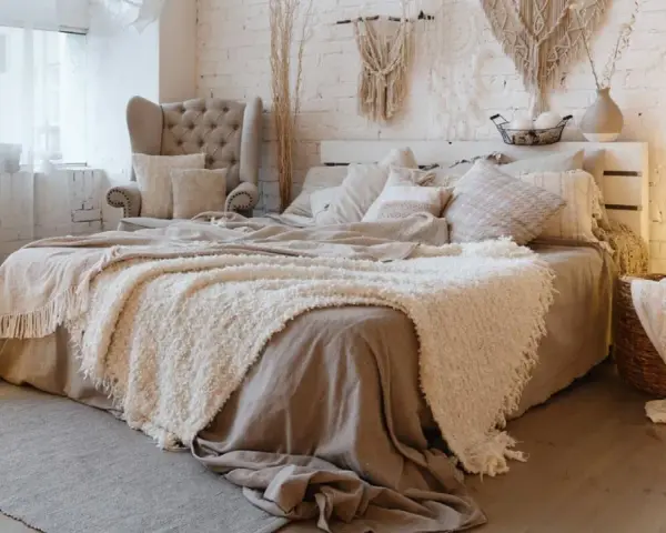Acogedora decoracion boho habitacion con cama mullida, sillón, macramé y faroles.