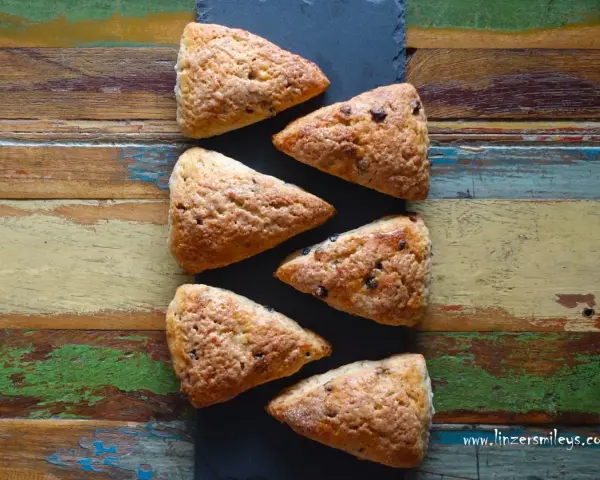 Sechs dreieckige Schokoladen-Scones liegen auf einem rustikalen Holztisch. Perfekt für alle, die keine komplizierten discard rezepte mögen.