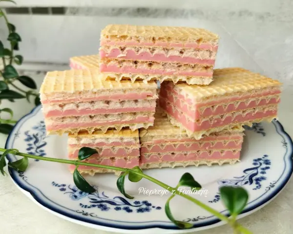 Piękne wafle z mlekiem w proszku, ułożone na talerzyku z niebieskimi wzorami, ozdobione zielonymi listkami.