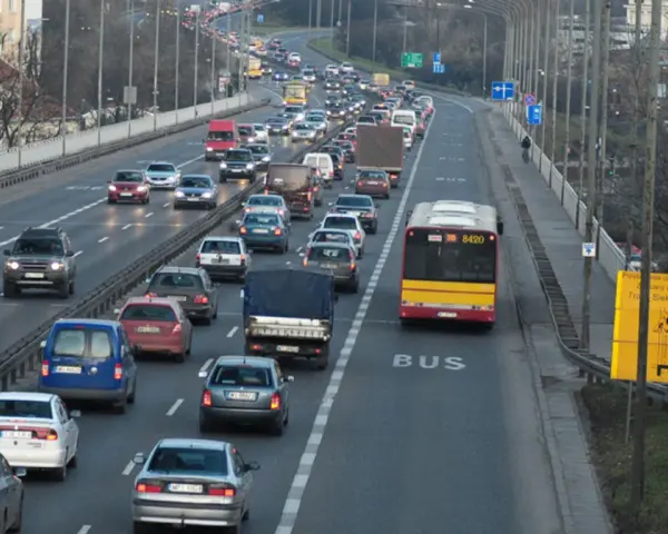 Autobus jedzie pasem dla autobusów. Wokół ruch samochodowy.