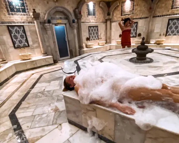 Kobieta w pianie w łaźni hammam. To tradycyjne tureckie łaźnie parowe, miejsce relaksu i oczyszczenia.