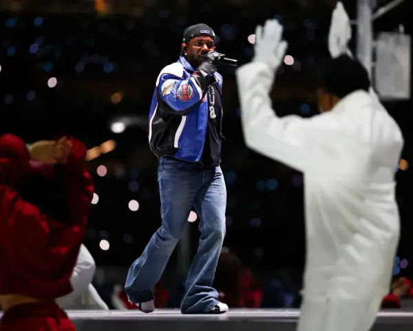Un rappeur sur scène, micro en main, devant une foule lumineuse. Une performance qui rappelle l'énergie du rap francais.
