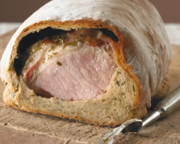 Saftiges Kassler im knusprigen Brotmantel, bereit zum Anschneiden. Ein Festmahl!