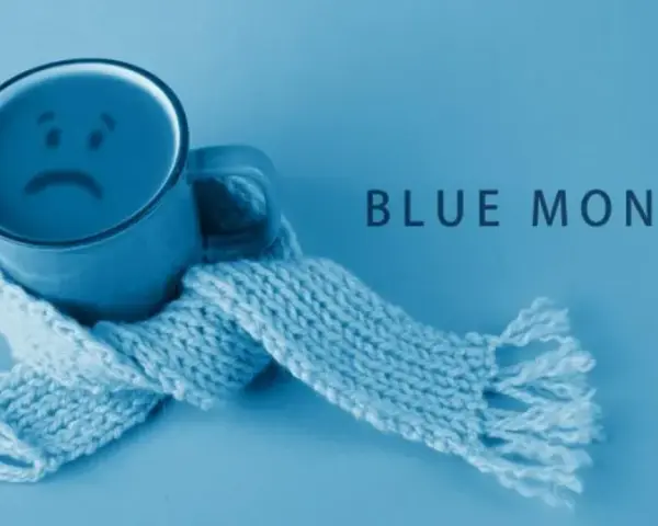 Smutny kubek z uśmiechem, otulony szalikiem, symbolizuje blue monday.