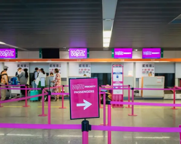 Kasa Wizz Air, gdzie pasażerowie dokonują self check-in. Różowe taśmy wyznaczają kolejkę do stanowisk odprawy.