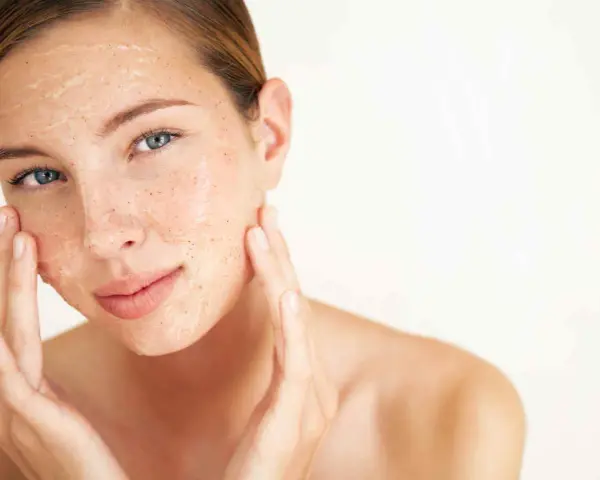 Mujer aplicándose una mascarilla exfoliante con vinagre de manzana para la cara. Sus dedos masajean suavemente el producto.