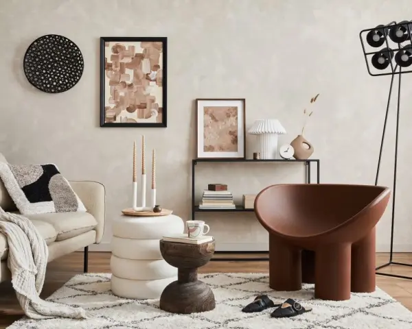 Przytulny salon z kanapą w tkaninie boucle, ozdobiony abstrakcyjnym obrazem i designerskim fotelem.