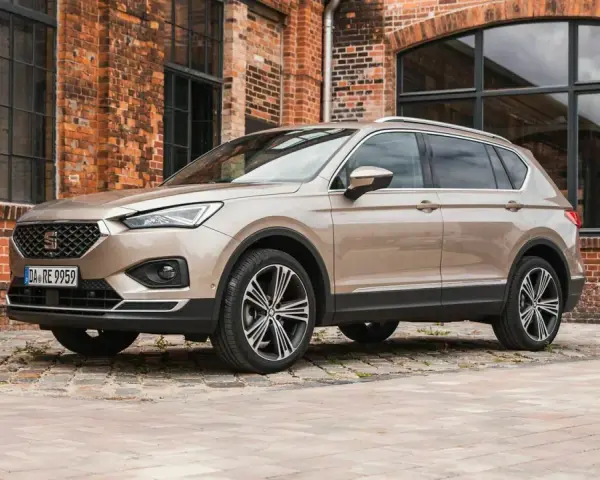 Beiger Seat Tarraco vor Backsteinhaus. Keine Seat Tarraco Probleme hier, nur stilvolles Fahren.