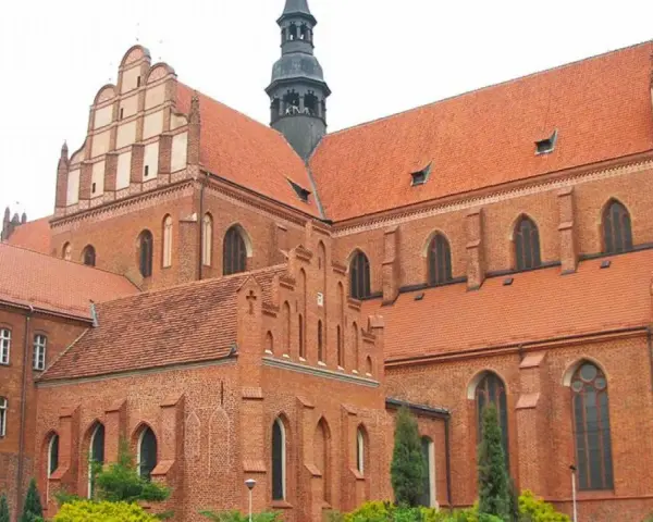 Potężny zamek krzyżacki w Pelplinie, z cegły i czerwonym dachem, góruje nad okolicą.