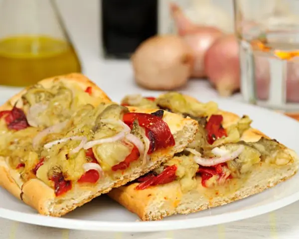 Dos porciones de coca de recapte con verduras asadas, pimientos rojos y cebolla.