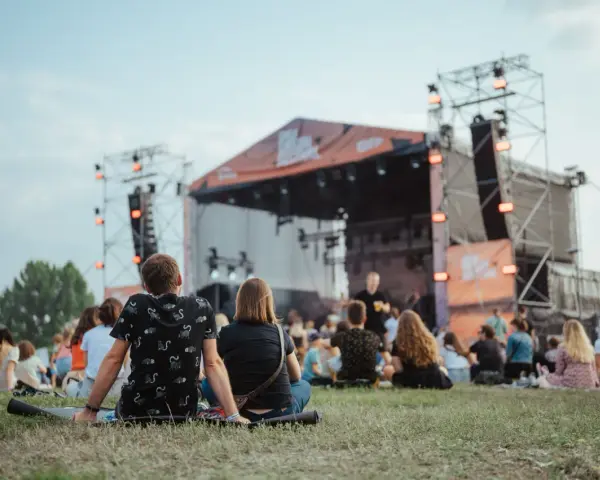 Widownia siedzi na trawie przed sceną podczas Enea Festival Baranowo.
