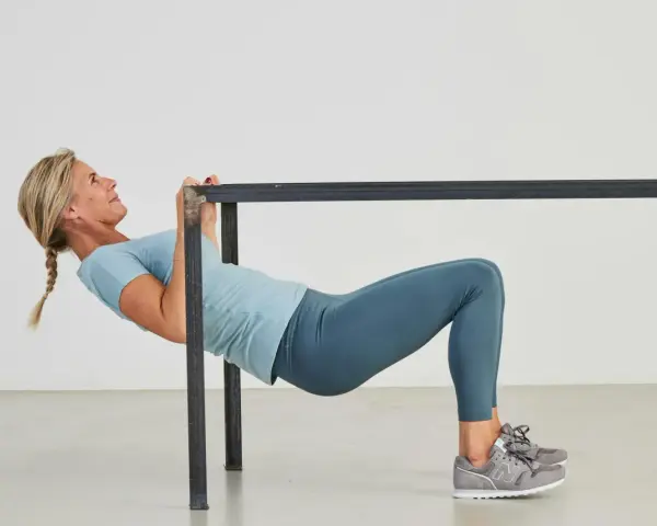 Kvinna utför overhead triceps extension vid en ställning.