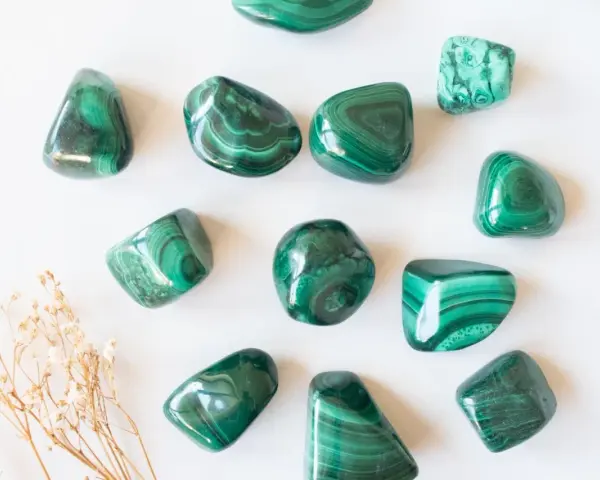 Tumbled malachite stones with their characteristic green bands, showcasing the beauty and potential malachite proprietà.