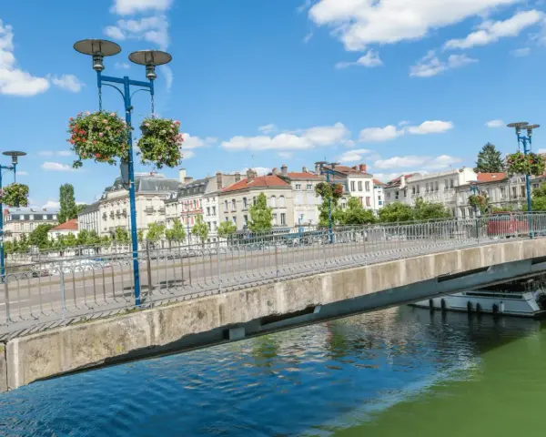 Pont fleuri sur la Meuse, une belle journée pour visiter Verdun en 1 jour. Ville historique avec des bâtiments anciens et un ciel bleu.