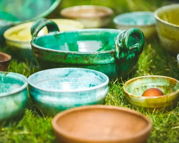 Varietà di ciotole in ceramica smaltata, che ricordano diversi tipi di argilla per modellare, disposte sull'erba.