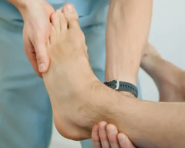 Fizjoterapeuta bada stopę pacjenta, zastanawiając się, jak długo boli noga po złamaniu kostki.