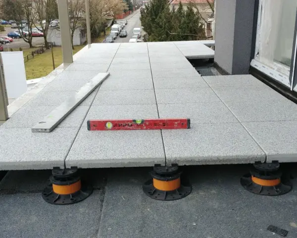 Układanie płyt na wspornikach tworzy wentylowany balkon. Poziomica zapewnia idealne dopasowanie.